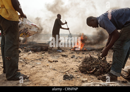 Teenage boys burn cables from computers and other electronics to recover copper near the Agbogboloshie slum in Accra, Ghana Stock Photo