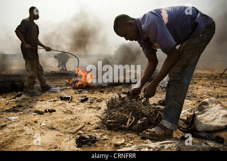 Teenage boys burn cables from computers and other electronics to recover copper near the Agbogboloshie slum in Accra, Ghana Stock Photo