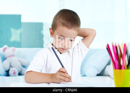 Pensive kid being busy doing his homework Stock Photo