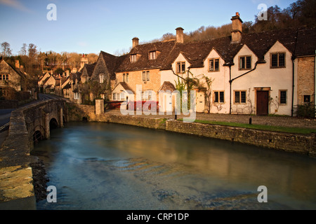 The River Bybrook, a tributary of the Bristol Avon, flowing under a bridge through the village of Castle Combe. Stock Photo