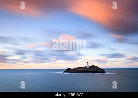 Sunset over Godrevy lighthouse, built in the mid 19th century to warn shipping of the danger of a submerged reef known as the St Stock Photo