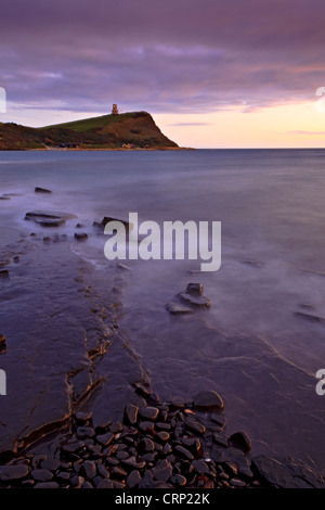 View over rocky ledges in Kimmeridge Bay towards Clavell Tower, a Tuscan style tower built in 1830 on Hen cliff on the Jurassic Stock Photo