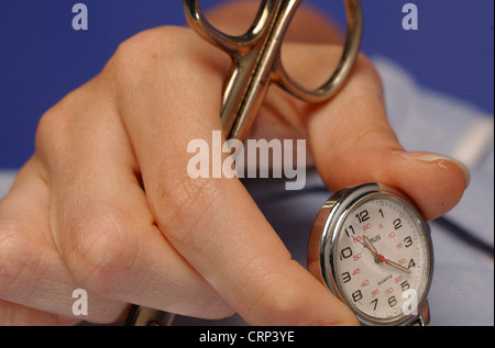 Nurse holding a fob watch and a pair of scissors. Stock Photo