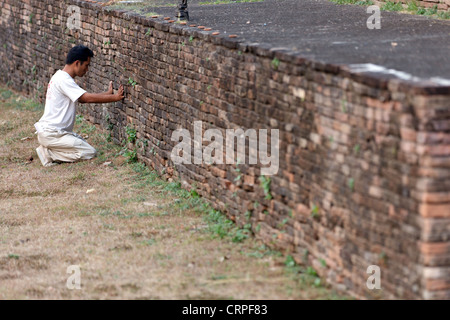 Thai man praying against old brick wall in Chiang Mai, Thailand Stock Photo