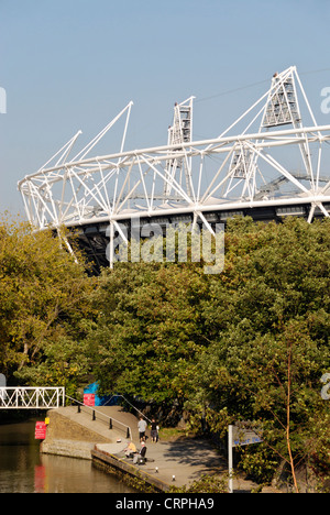 People walking along the riverside on the Lea Valley Walk with the Olympic Stadium in the background. Stock Photo