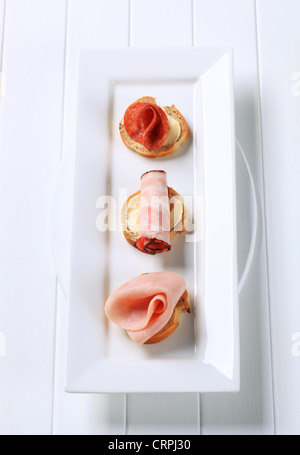 Ham and salami canapes on white plate Stock Photo