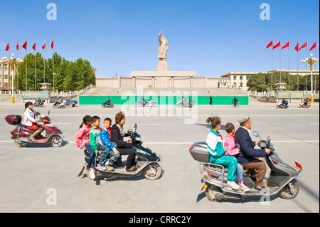 With motion blur.  Vehicles and people travel past the statue of Mao Zedong opposite the city square in Kashgar. Stock Photo