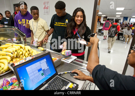 Cafeteria worker uses hand-held scanner to read barcode information on students school lunch cards at public charter high school Stock Photo
