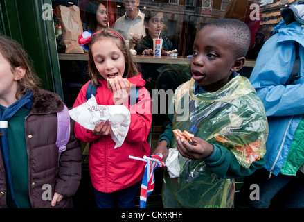 Young children eating hamburgers in the street Stock Photo