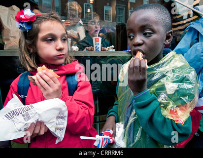 Young children eating hamburgers in the street Stock Photo