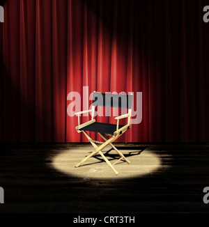A directors chair on a stage with a red curtain and spotlight Stock Photo