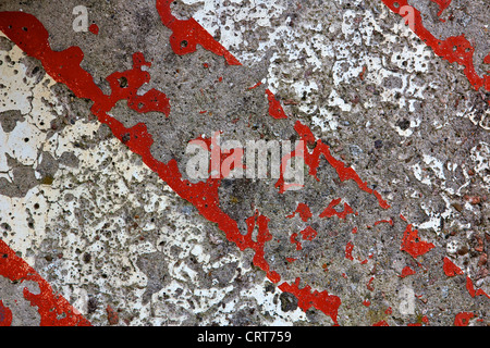 Detail of a pockmarked concrete wall painted in alternating bars of red and white at an industrial facility. Stock Photo
