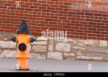 Typical fire hydrant against a brick wall on a city street Stock Photo