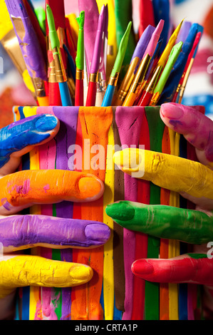 Close-up of woman holding multicolored paint can with painted fingers Stock Photo