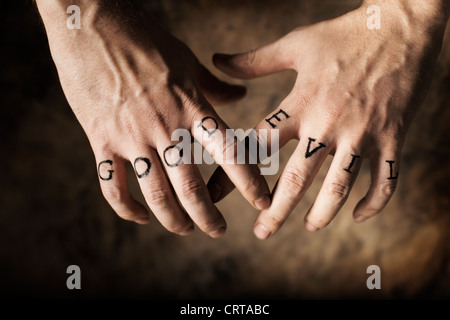 Man with Good and Evil (fake) tattoos on his hands. Stock Photo