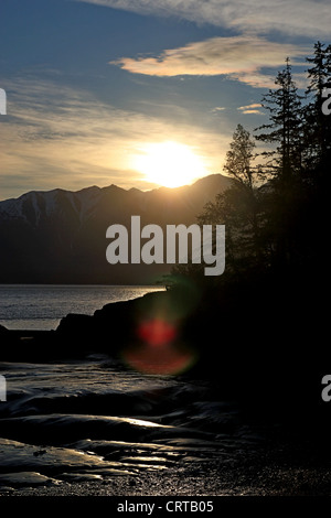 Sunset on a beach of the Turnagain Arm of the Cook Inlet on the Kenai Peninsula in Alaska with lens flair. Stock Photo