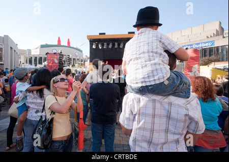 Woman taking a picture of a child on the shoulders of a man during the Just for Laughs festival in Montreal, province of Quebec, Stock Photo