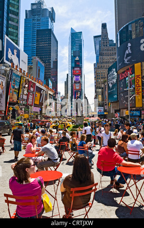 Tourists sitting outside in Times Square, New York City during daytime. Stock Photo