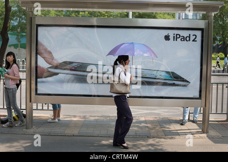 Shoppers pass an Apple iPad2 advertisement in the Sanlitun upmarket shopping district, in Beijing, China Stock Photo