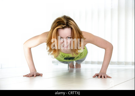 young woman doing push-ups on the floor Stock Photo