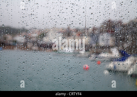 Rain drops on the windows of the ferry to Herm overlooking St Peter Port harbour, Guernsey Stock Photo