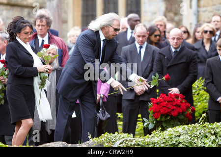 Barry Gibb (centre), brother of Robin Gibb, throws a rose onto the coffin at the funeral from the Bee Gee singer. Stock Photo