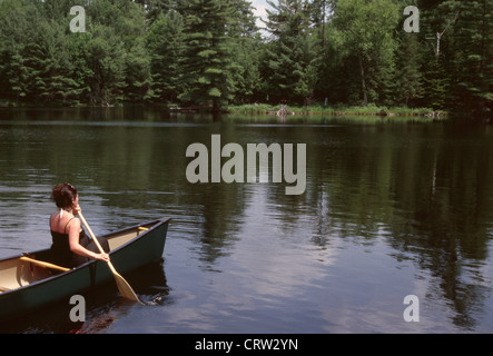 A woman canoeing on a lake in the Adirondacks, in upstate New York. Stock Photo