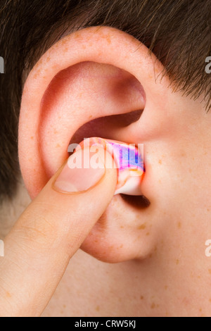Touch Ear Color color earplug into the ear close up Stock Photo - Alamy