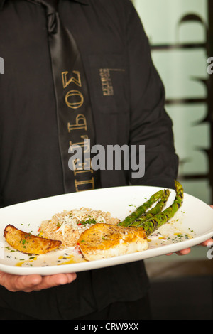 man serving sauteed sea bass with asparagus, Petros Greek Restaurant, Santa Barbara, California