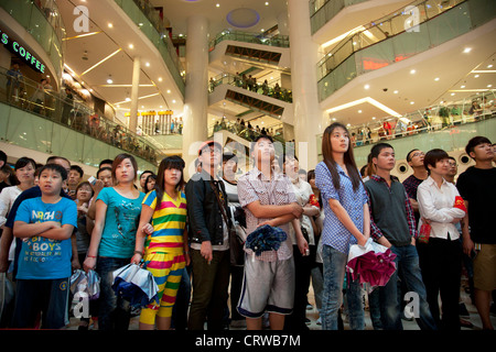 Crowds of shoppers watch a massive PR promotional event by cell phone ...