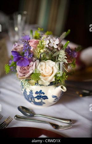 flower bouquet displayed in a teapot at a table setting Stock Photo