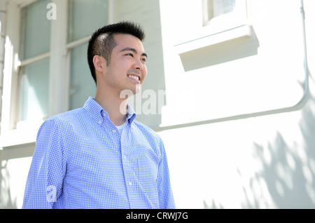 Head shot of a young Asian man smiling taken from a low angle Stock Photo