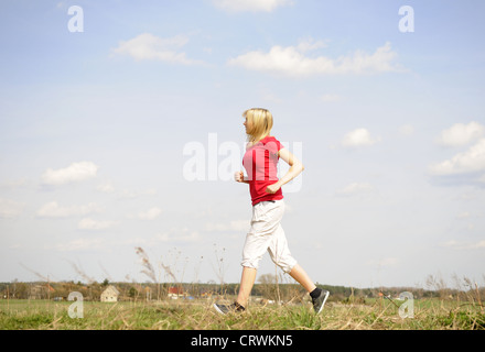 young woman jogging on a dirt road Stock Photo
