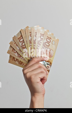 Man holding new Canadian $100 bills made from plastic polymer designed to help the bills last longer. Stock Photo