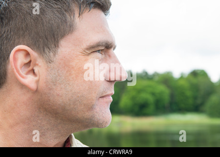 Side view portrait of man standing by a lake Stock Photo
