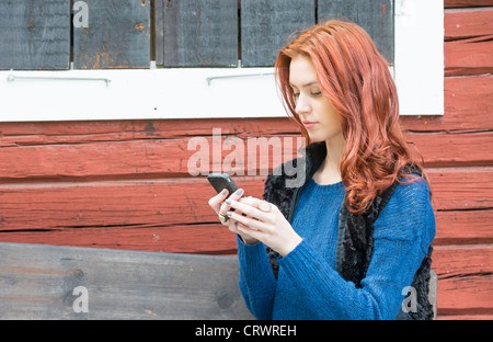 Young female adult with red hair checking her mobile phone Stock Photo