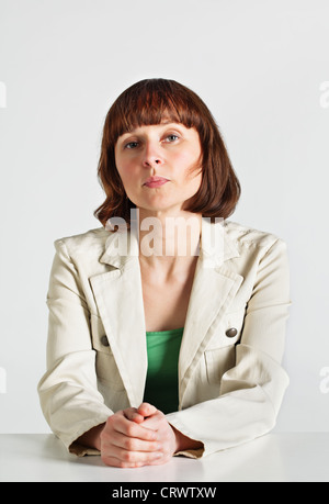 Serious middle age teacher sitting behind the desk Stock Photo