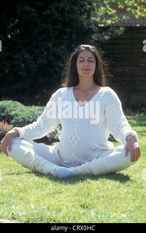pregnant woman meditating in garden Stock Photo
