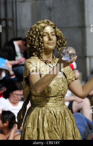 Female street performer painted in gold. Stock Photo