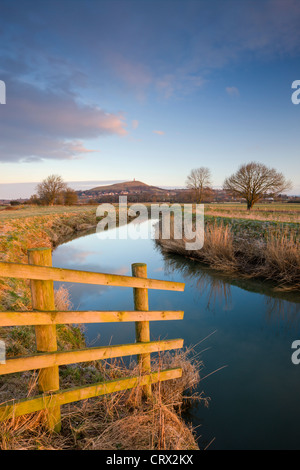First light of morning on Glastonbury Tor viewed from the River Brue, Somerset Levels, Glastonbury, Somerset, England.