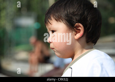 It's Chinese Eurasian baby Boy who is the center of this photo. he thinks dreams literally drinking life. He sits on wood chair Stock Photo