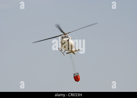 Firefighter helicopter in flight carrying a extinguising bucket Stock Photo