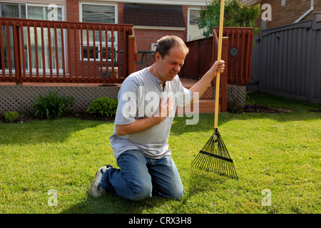 man having a heart attack chest pains while doing yard work Stock Photo