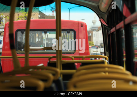 a view along the top deck of a London double decker bus including other buses traveling in front Stock Photo