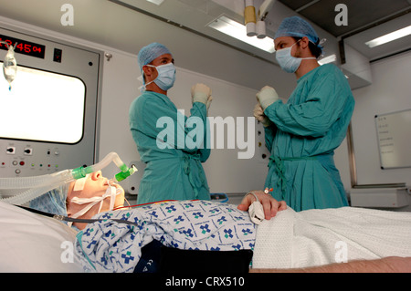 A young female patient, wearing a blue surgical cap, in an operating theater. Stock Photo