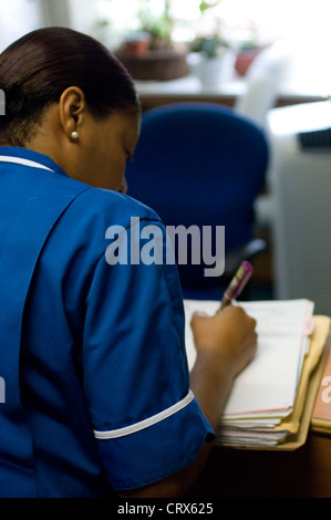 A nurse in a dark blue uniform writing up patient notes Stock Photo