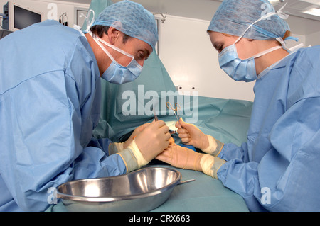 A surgeon operating on a patient's hand, assisted by a scrub nurse. Stock Photo