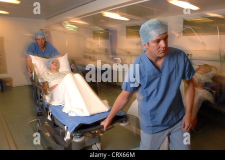 Two hospital porters wheeling patient on trolley bed to operating ...