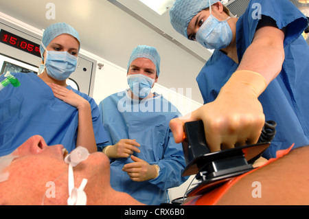 Doctors using a defibrillator to resuscitate a male heart attack victim. Stock Photo