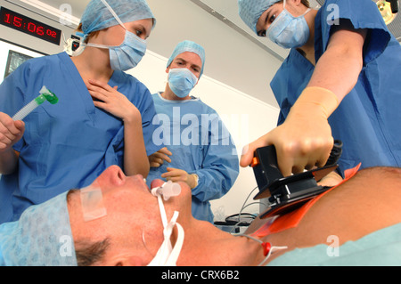 Doctors using a defibrillator to resuscitate a male heart attack victim. Stock Photo